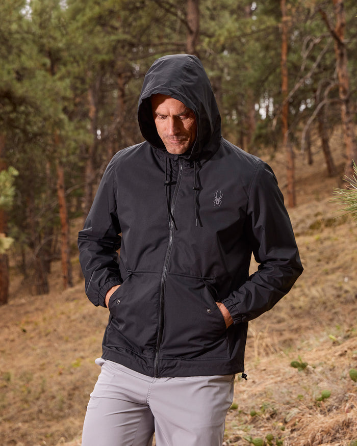 Person wearing a black jacket with a hood in a forest setting