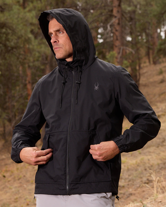 Person wearing a black jacket with a hood in a forest setting