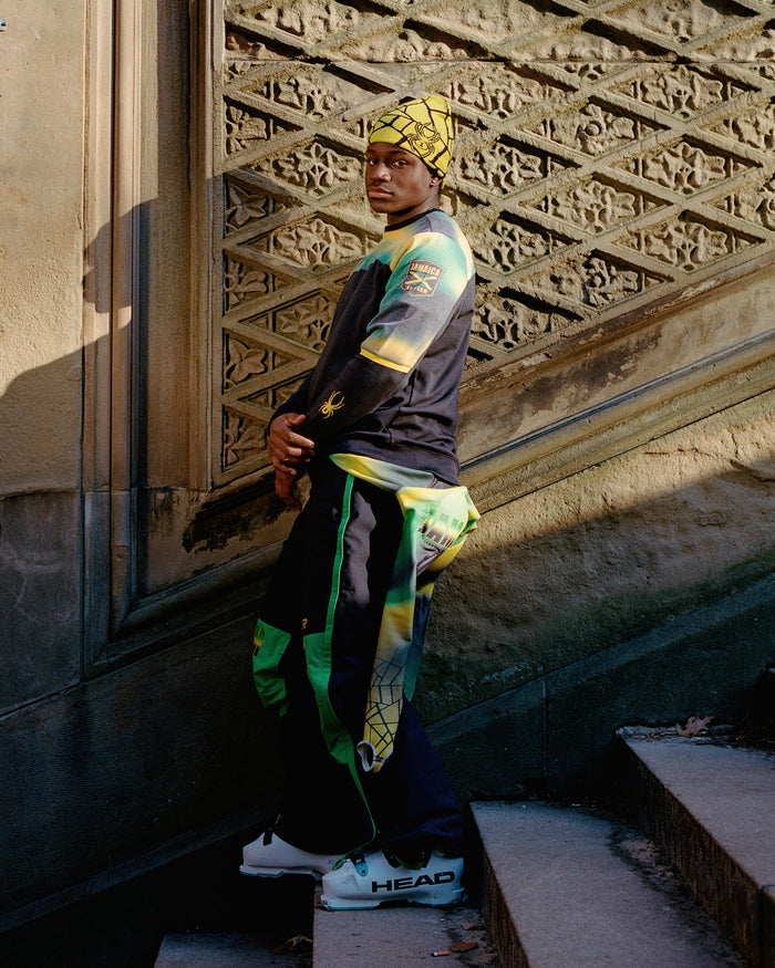 Person wearing a colorful outfit with a patterned wall in the background