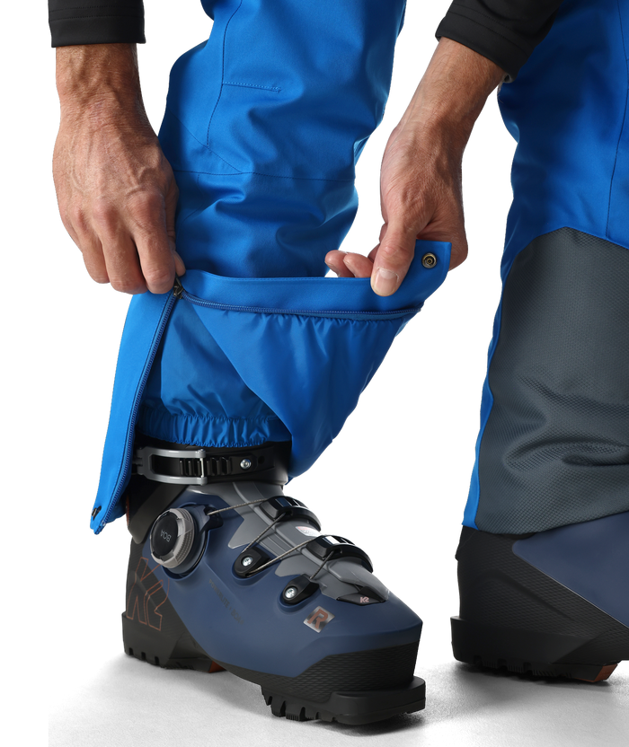 Person wearing blue ski pants with a boot attached, on a white background