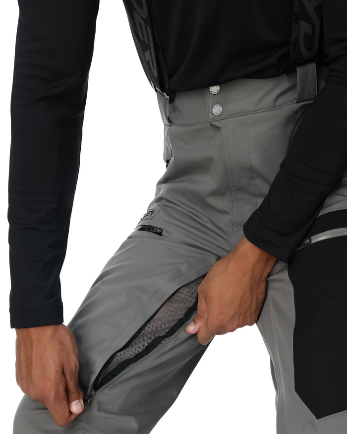 Person wearing gray pants with a black jacket on a white background