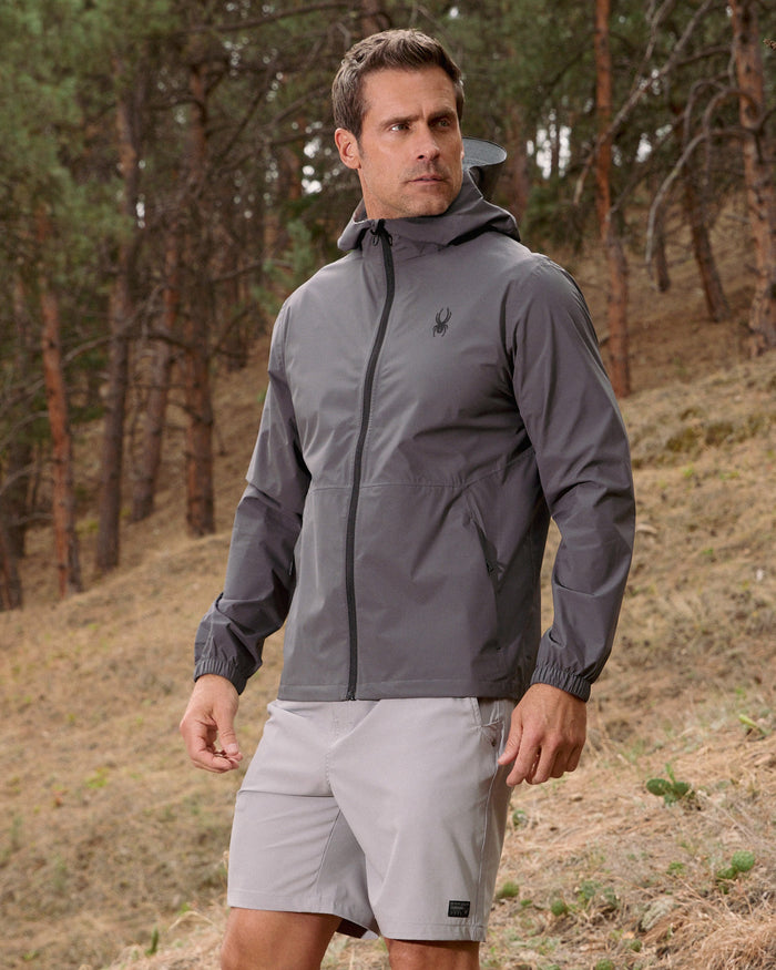 Man wearing a gray jacket and shorts in a forest setting