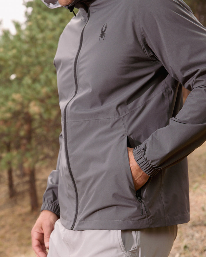 Person wearing a gray jacket with a brand logo outdoors