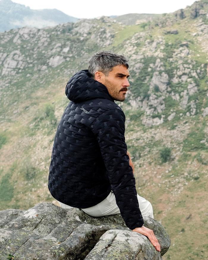 Man sitting on a rock with a mountainous landscape in the background