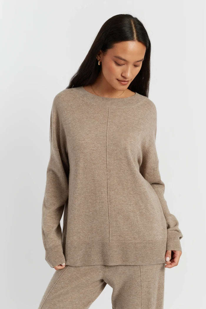 Woman wearing a beige sweater and pants on a white background