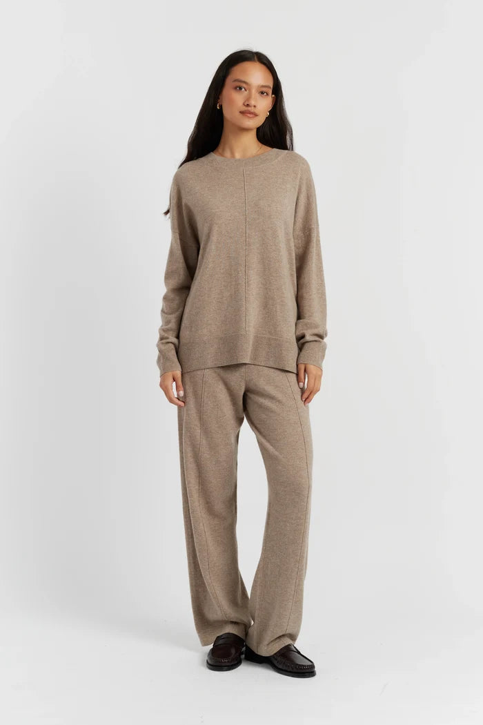 Woman wearing a beige sweater and pants set on a white background