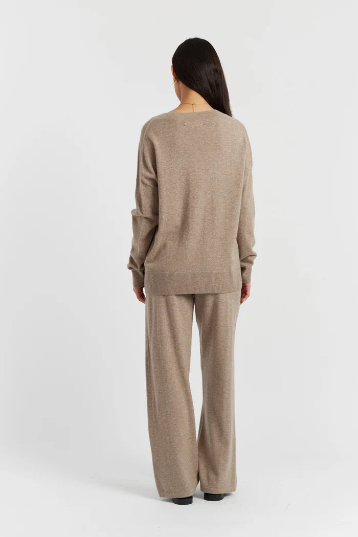 Person wearing a beige sweater and pants set on a white background