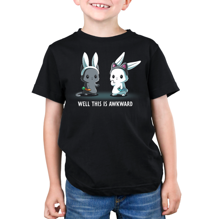 Premium Cotton T-shirt_TeeTurtle black Well This Is Awkward Premium Cotton T-shirt featuring a a cat in bunny ears holding a carrot and a bunny in cat ears holding a piece of fish. Both look unsettled. Text at the bottom reads "Well This Is Awkward"